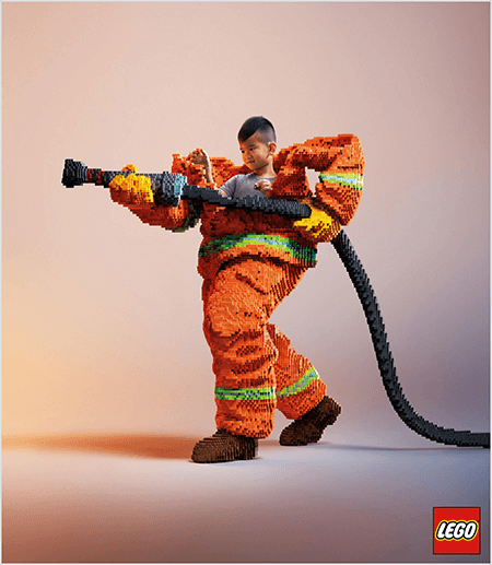 Tämä on kuva LEGO-mainoksesta, jossa nuori aasialainen poika näkyy LEGO-palomiespuvussa. Virkapuku on oranssia ja neonvihreä raita takin ja housujen hihansuissa. Palomies seisoo yhdellä jalalla taaksepäin ja pitää kiinni tulipesästä, joka on myös valmistettu legoista. Pojan pää ilmestyy univormun yläosasta, joka on paljon suurempi kuin hän on ja pysähtyy hartioiden ympäri. Kuva on otettu tavallista neutraalia taustaa vasten. LEGO-logo näkyy punaisessa laatikossa oikeassa alakulmassa. Talia Wolf sanoo, että LEGO on loistava esimerkki brändistä, joka käyttää tunteita mainonnassa.