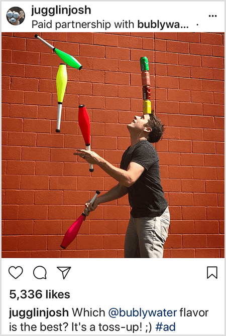 Josh Horton taistelee mailoja, jotka sopivat hänen päähänsä pinottujen neljän Bubly-vesipullon väreihin. Tausta on punainen tiiliseinä. Kuva on mainos, jonka Josh loi Bubly-vedelle ja joka julkaistiin Instagram-syötteessään kuvauksella Mikä Bubly Water Flavor on paras? Se on Toss Up!