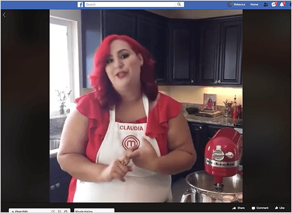 Tämä on kuvakaappaus Facebook Live -videosta, jossa on mukana kokki Claudia Sandoval, jonka hän isännöi vuonna 2016 osana ristikampanjaa T-Mobile Tuesday-sovelluksen kanssa. Videossa Claudia seisoo keittiössä, jossa on mustat kaapit ja graniittiset työtasot. Ikkunan yli pesuallas päästää luonnonvaloa huoneeseen. Claudia seisoo punaisen Kitchen Aid -sekoittimen vieressä. Hän on latinalainen nainen, jolla on kirkkaan punaiset hiukset, jotka putoavat hieman hänen harteidensa alle. Hänellä on meikki, kirkkaan punainen yläosa ja valkoinen esiliina, jossa Claudia ja MasterChef-logo on brodeerattu punaisella langalla. Puhuessaan hän elehtii käsillään. Vuonna 2016 Stephanie Liu teki yhteistyötä Claudian kanssa tämän live-videon tuottamiseksi.