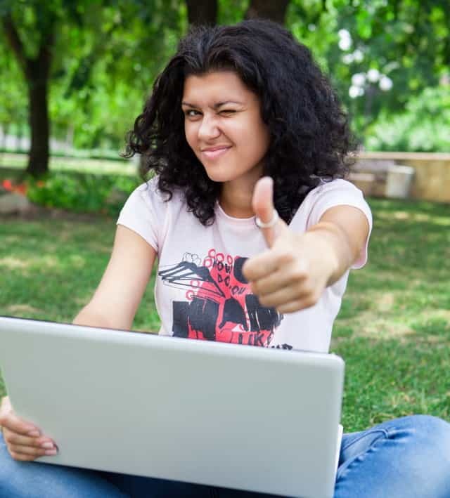 Tyttö kannettavan tietokoneen puistossa